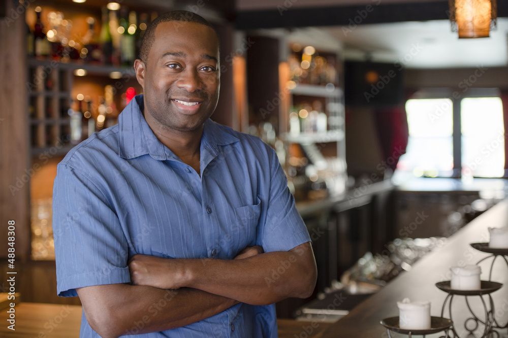African American owner standing in bar