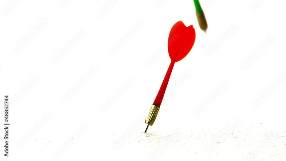 Red and green darts piercing white surface in slow motion Red and green darts piercing white surface in slow motion
