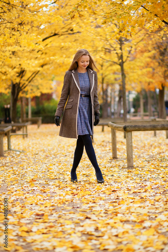 Beautiful young girl walking in park on a fall day