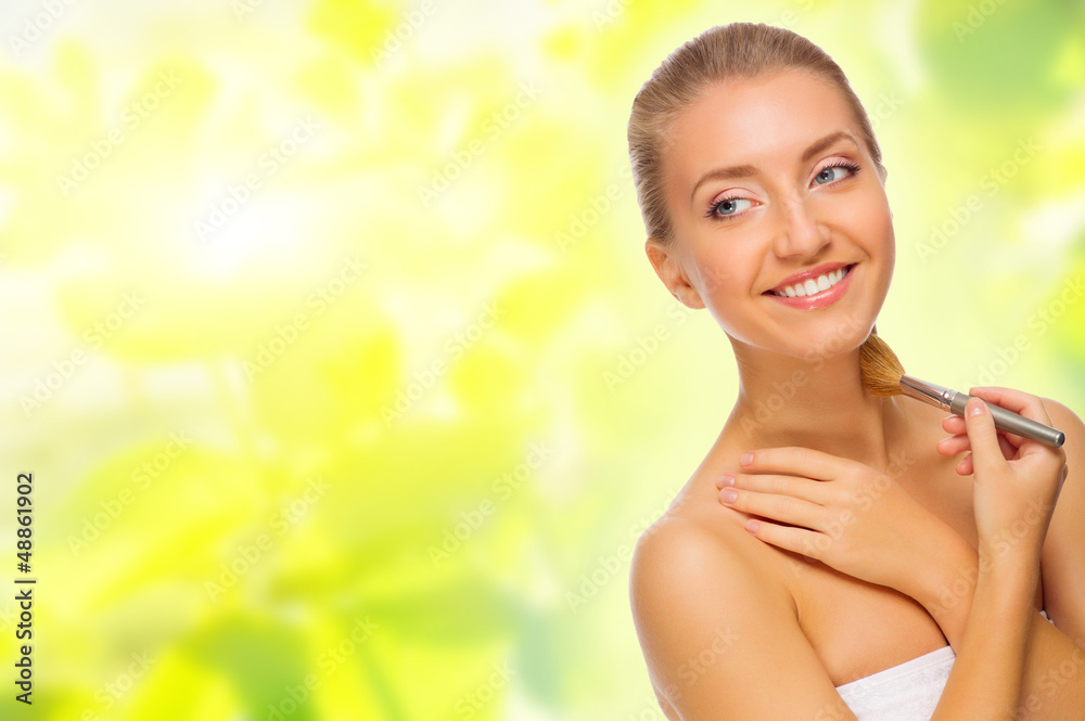 Young woman with makeup brush on spring background Young woman with makeup brush on spring background