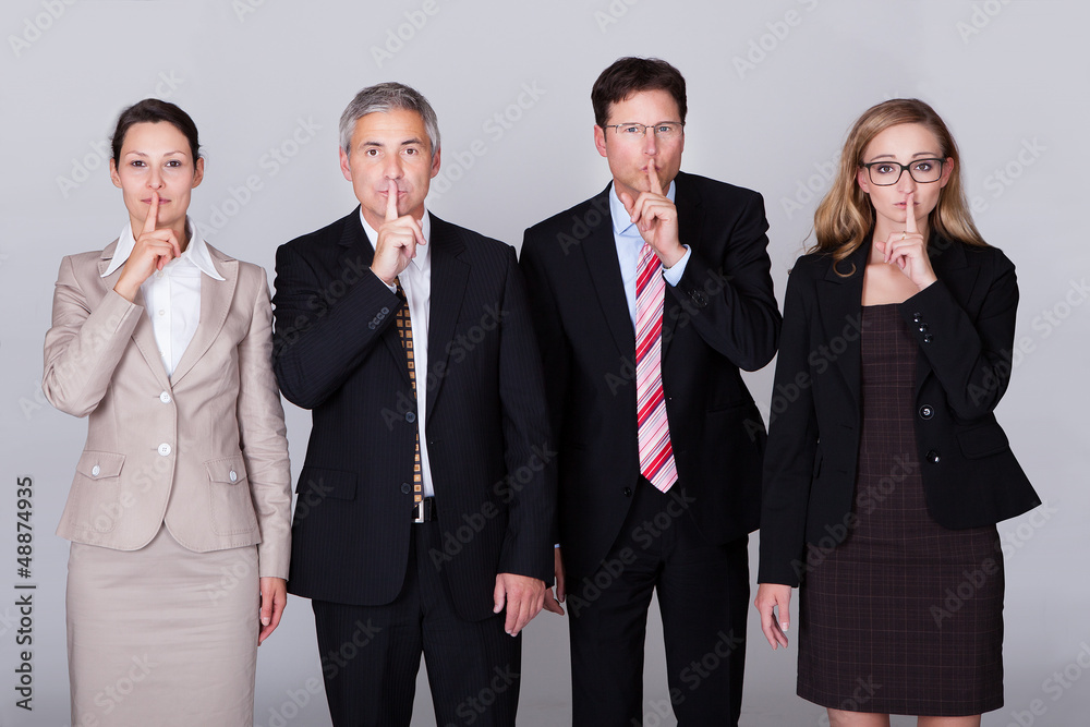 Four businesspeople gesturing for silence Four businesspeople gesturing for silence