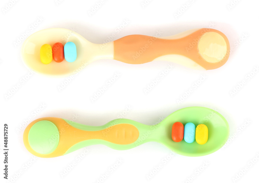 Plastic spoons with color pills, isolated on white Plastic spoons with color pills, isolated on white