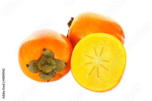 Three kaki fruits, one cut in half