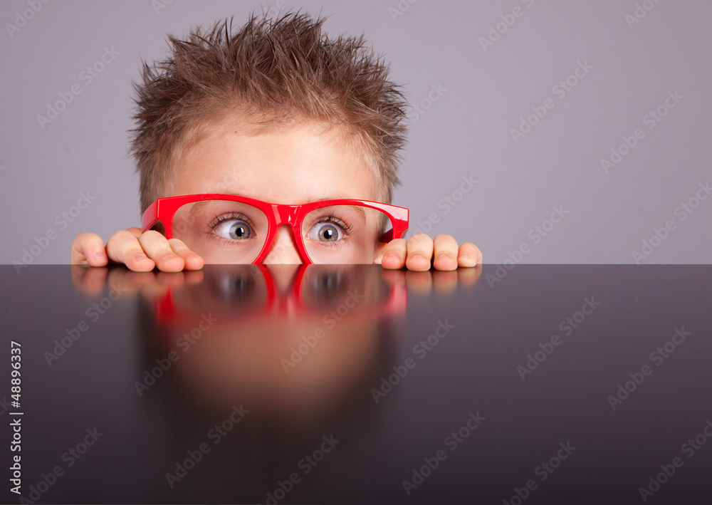 Five years old little cute boy hiding behind a table - obrazy, fototapety, plakaty 