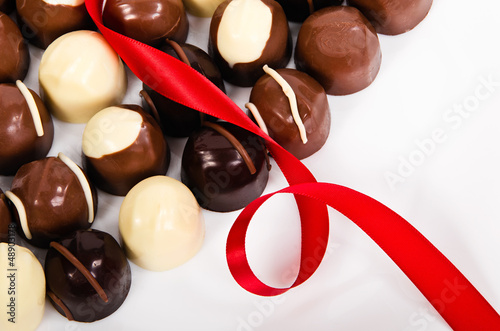 Assortment of dark and white chocolate candies with red ribbon