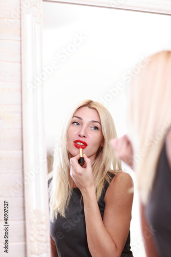 Young woman applying red lipstick 