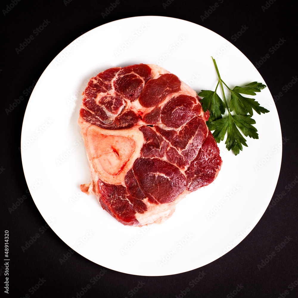 Raw beef with bone on white plate