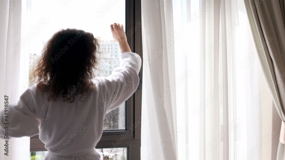 Woman comes to draws curtains and watch street outside window Woman comes to draws curtains and watch street outside window