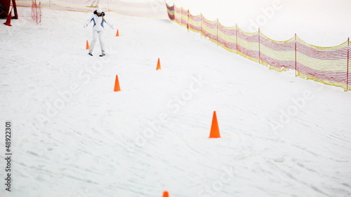 inexperienced girl on skis goes down hill perambulate barriers photo