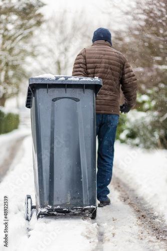 Man moving dustbin in the snow photo