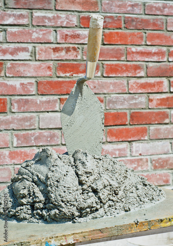 Bricklayers trowel and grout in fromnt of brick wall