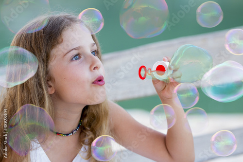 Summer joy - lovely girl blowing soap bubbles