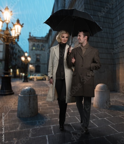 Photography Elegant couple with umbrella outdoors on rainy evening