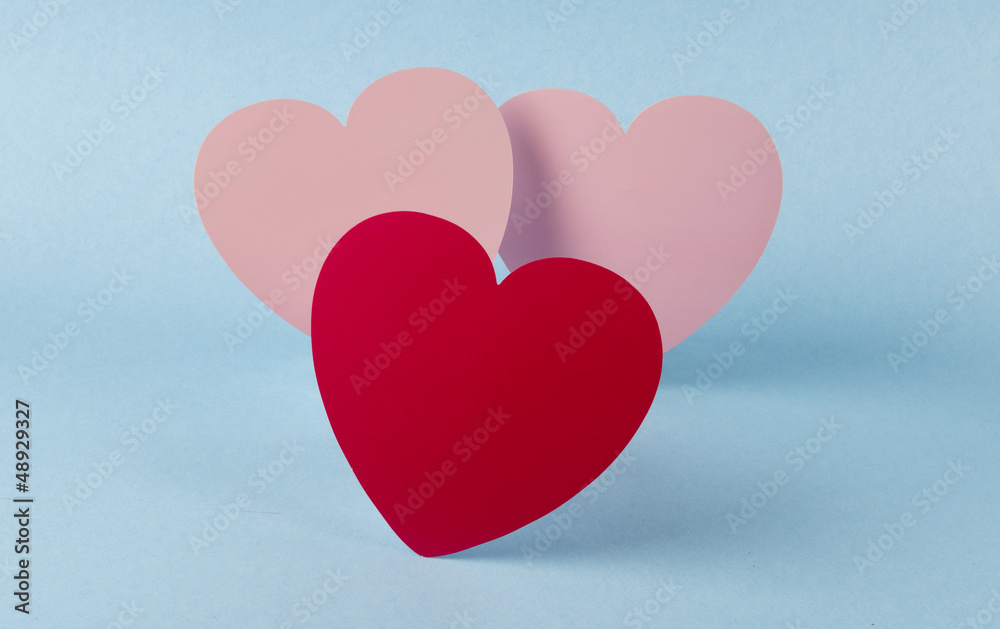 One Red heart and two pink hearts  on blue background