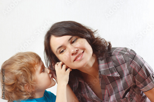 Little boy whispers something to his mother