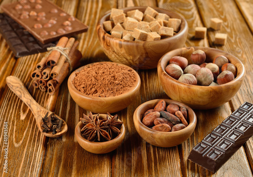 Nuts, spices and cocoa in a wooden bowl on a brown table