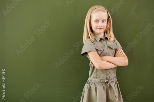 Scoolgirl standing near blackboard © Sergey Nivens