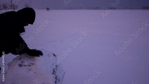ragazzo spinge palla di neve in inverno al freddo photo