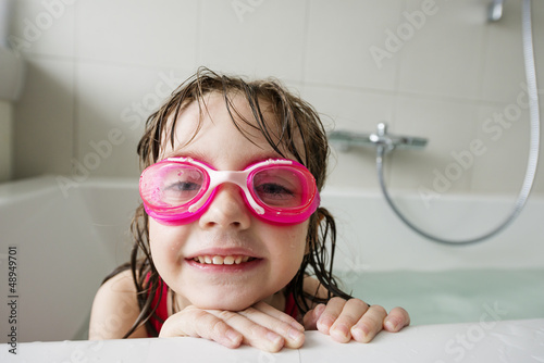 a happy  little girl with swim glasses bathing photo