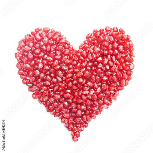 ripe pomegranate seeds in form of heart isolated on white backgr