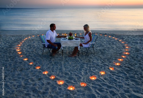 Fototapeta A young lovers couple share a romantic dinner with candles heart