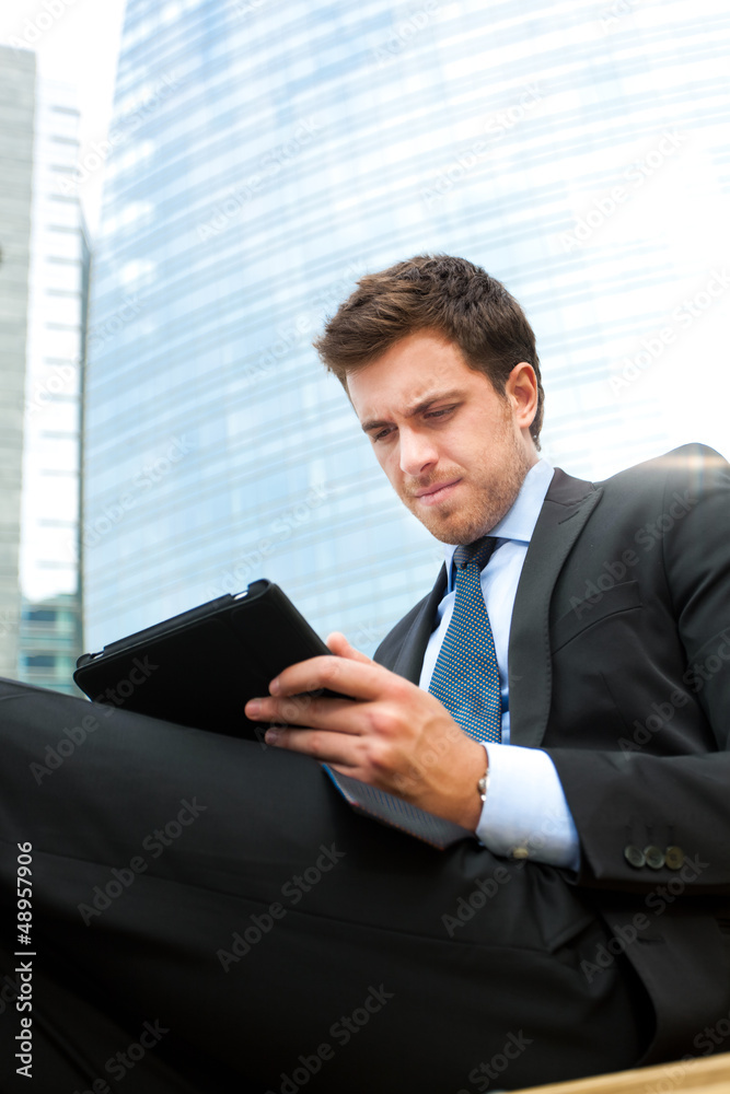Fototapeta premium Businessman using a tablet on a bench in the city