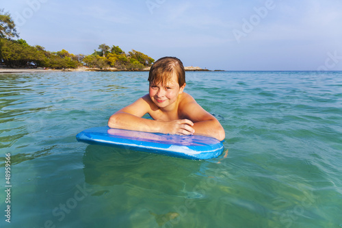 boy is swimming on his surfboard