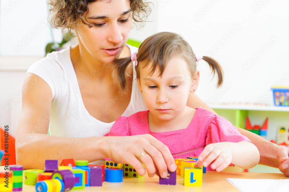 Young mother and little daughter playing with toy blocks Young mother and little daughter playing with toy blocks