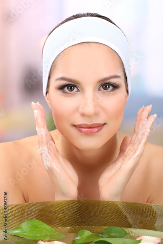 Young woman washing her fac...