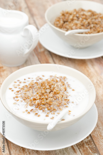 Boiled buckwheat with milk in a white bowl vertical © cook_inspire