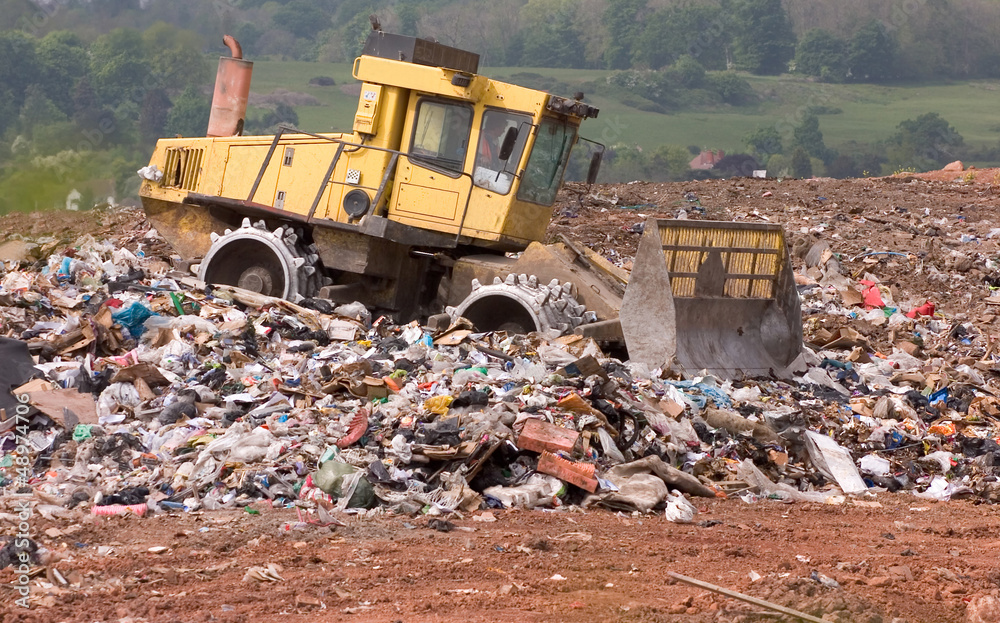 A bulldozer moving garbage on a landfill waste site A bulldozer moving garbage on a landfill waste site