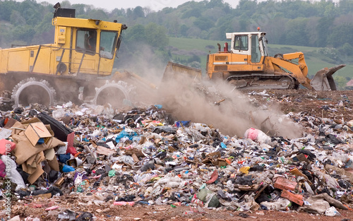 Bulldozers moving garbage on a landfill waste site