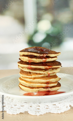 Sweet pancakes on plate with jam on table in kitchen