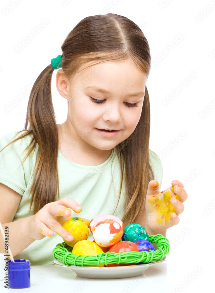 Little girl is painting eggs preparing for Easter Little girl is painting eggs preparing for Easter