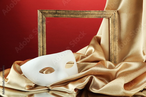 White mask, empty frame and golden silk fabric, photo