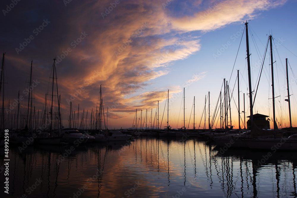 silhouettes of yachts in marina with magical sky