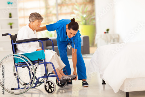 young caregiver helping elderly woman on wheelchair