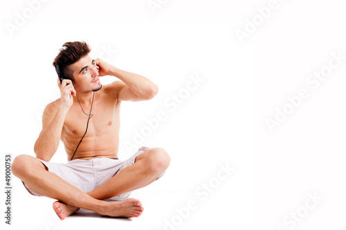 Young man sitting on the floor and listening to music with headp