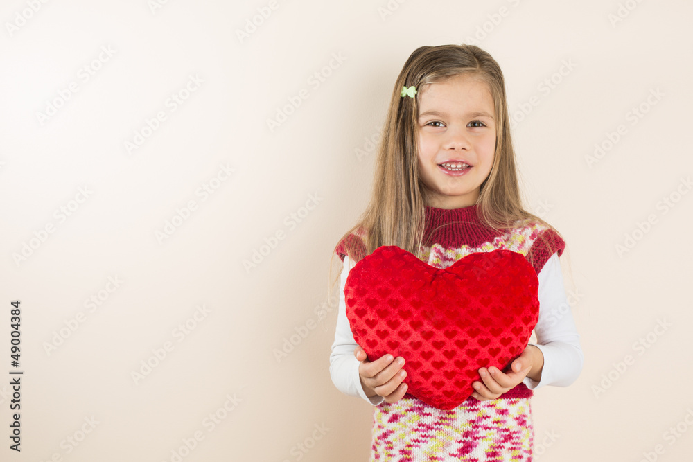 Little Girl Holding Heart-Shaped Pillow , against Pink Wall Little Girl Holding Heart-Shaped Pillow , against Pink Wall