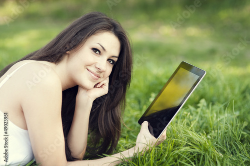 Young woman using digital tablet on meadow © gpointstudio