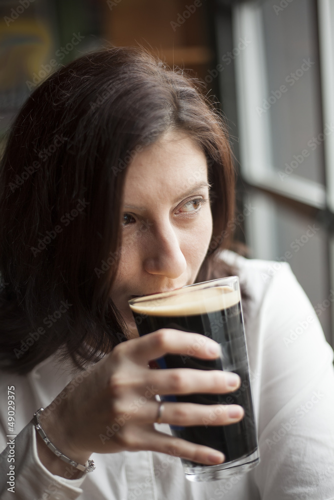 Young Woman with Beautiful Brown Eyes Drinking a Pint of Stout