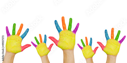 Painted hands raised up. Groups of children in classroom.