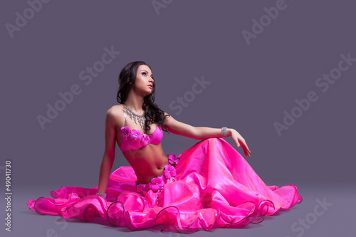 dancer in oriental pink costume sitting on floor