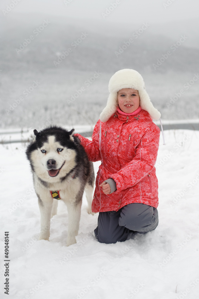 little girl sits with Husky
