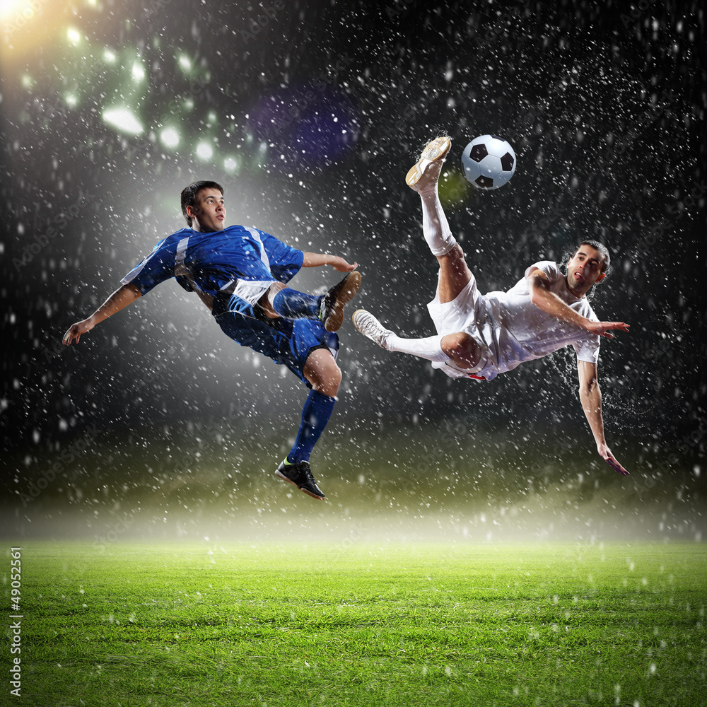 two football players striking the ball two football players striking the ball