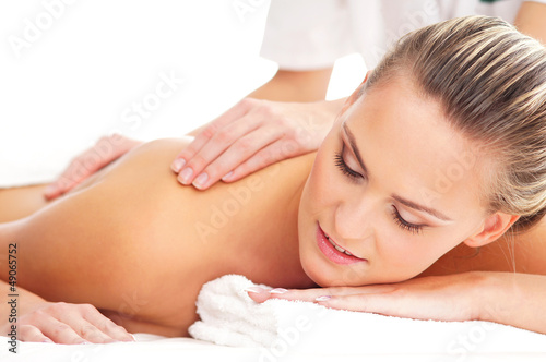 A young naked blond woman laying on a back massage