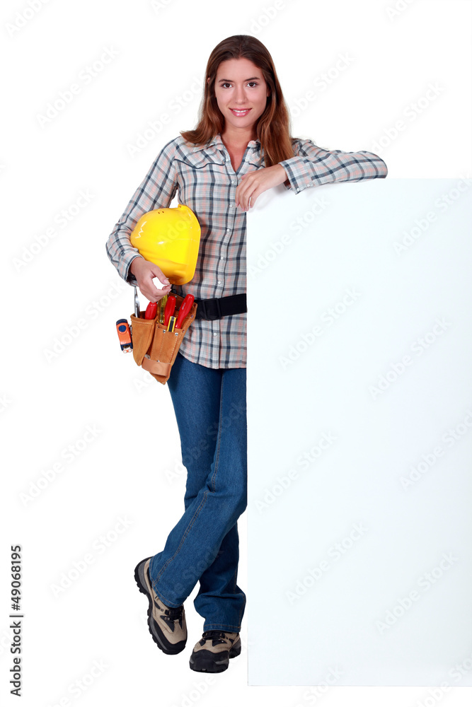 A female construction worker by a billboard. A female construction worker by a billboard.