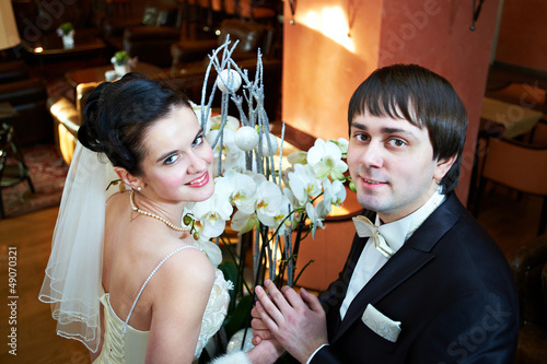 Happy bride and groom near flowers
