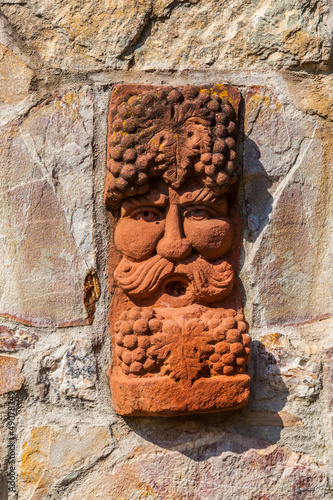 old medieval stone wall with face of baccus, the god of winery photo