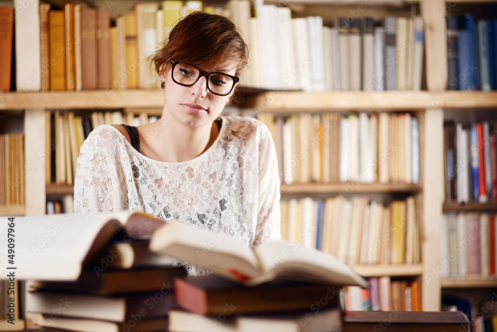 Student reading books and learning in front of a bookshelf Student reading books and learning in front of a bookshelf
